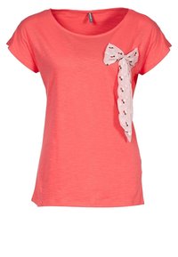 Koralowa koszulka z krótkim rękawem, z jasnoróżową kokardą z małymi nadrukowanymi detalami po lewej stronie. Miękka tekstura i luźny krój.