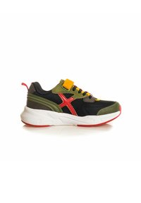 Zapatilla negra y verde con un acento rojo y una tira amarilla. Presenta una superficie texturizada, suela blanca gruesa y cordones multicolores.