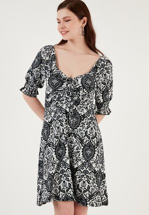 Black and white patterned dress with short puff sleeves, square neckline, and gathered detail at the front, featuring a flowing A-line shape.