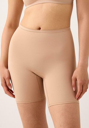 Beige seamless compression shorts, made of smooth fabric, featuring an elastic waistband and a mid-thigh length, with simple stitching details.