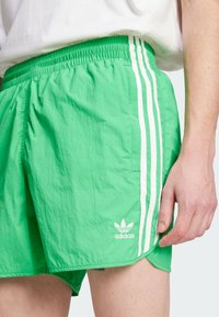 Πράσινα αθλητικά σορτς από ελαφρύ, υφαντό ύφασμα. Διαθέτουν λευκές ρίγες στο πλάι και κεντημένο λογότυπο adidas κοντά στο στρίφωμα.