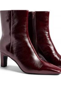 Bottines en cuir bourgogne avec une finition brillante, dotées d'un bout pointu et d'un talon carré de hauteur intermédiaire, avec une fermeture éclair sur le côté.