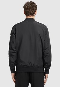 Schwarze Bomberjacke aus glattem Stoff, mit geripptem Kragen und Bündchen, elastischem Taillenbund und seitlichen Taschen.