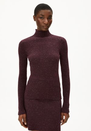 Burgunderfarbener Rippstrickoberteil mit Stehkragen, strukturiertem Material und dezentem Glanz. Lange Ärmel mit enganliegenden Bündchen, kombiniert mit einem passenden Rock.