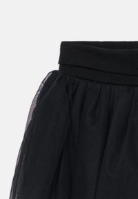 Svart tullskjørt med myk elastisk midje. Stoffet er lagdelt for volum med en lett, gjennomsiktig tekstur og en jevn finish ved livet.