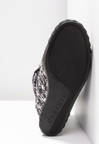Semelle de chaussure en caoutchouc noir texturé, marquage "CASADEI", et dessus en tissu tweed multicolore vu du dessous.