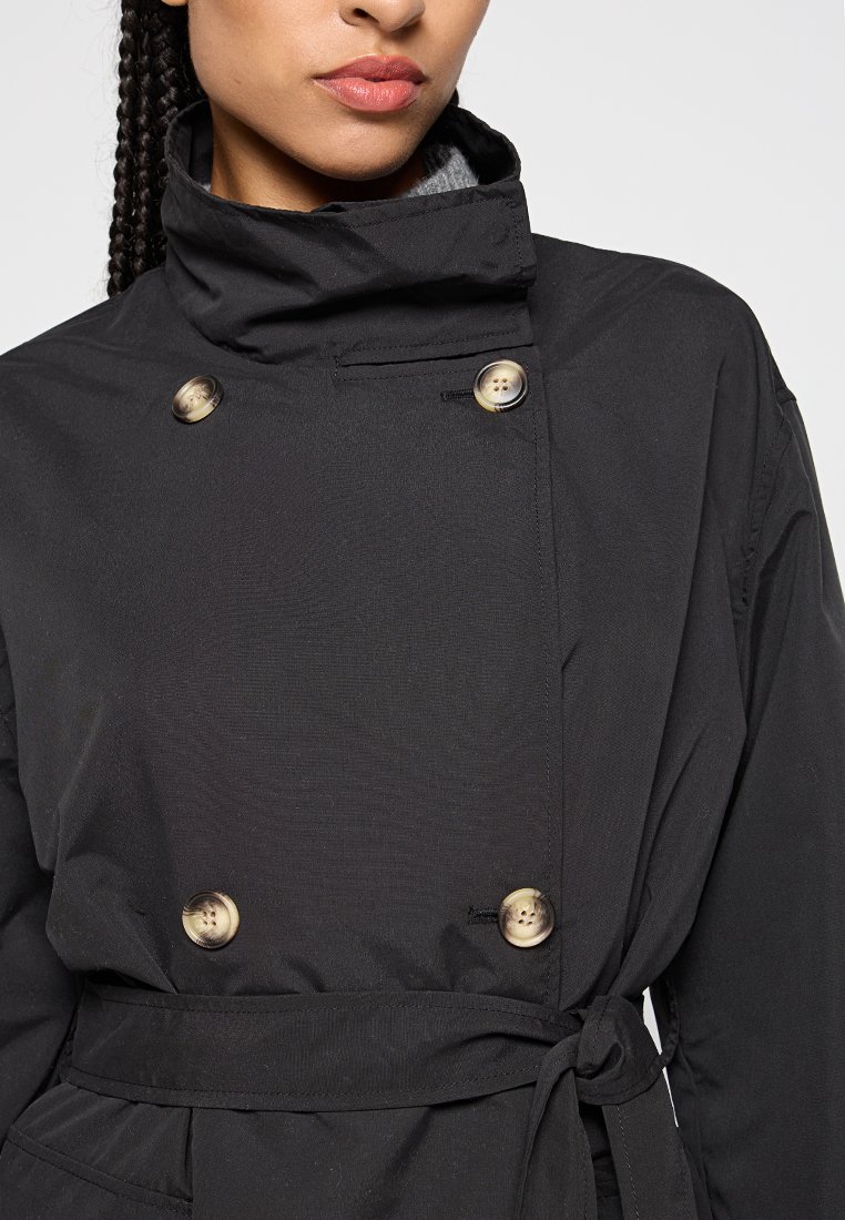 Schwarzer Trenchcoat mit hohem Kragen, doppelter Knopfleiste und gebundenem Taillengürtel. Verfügt über eine glatte Textur und ein strukturiertes Design.