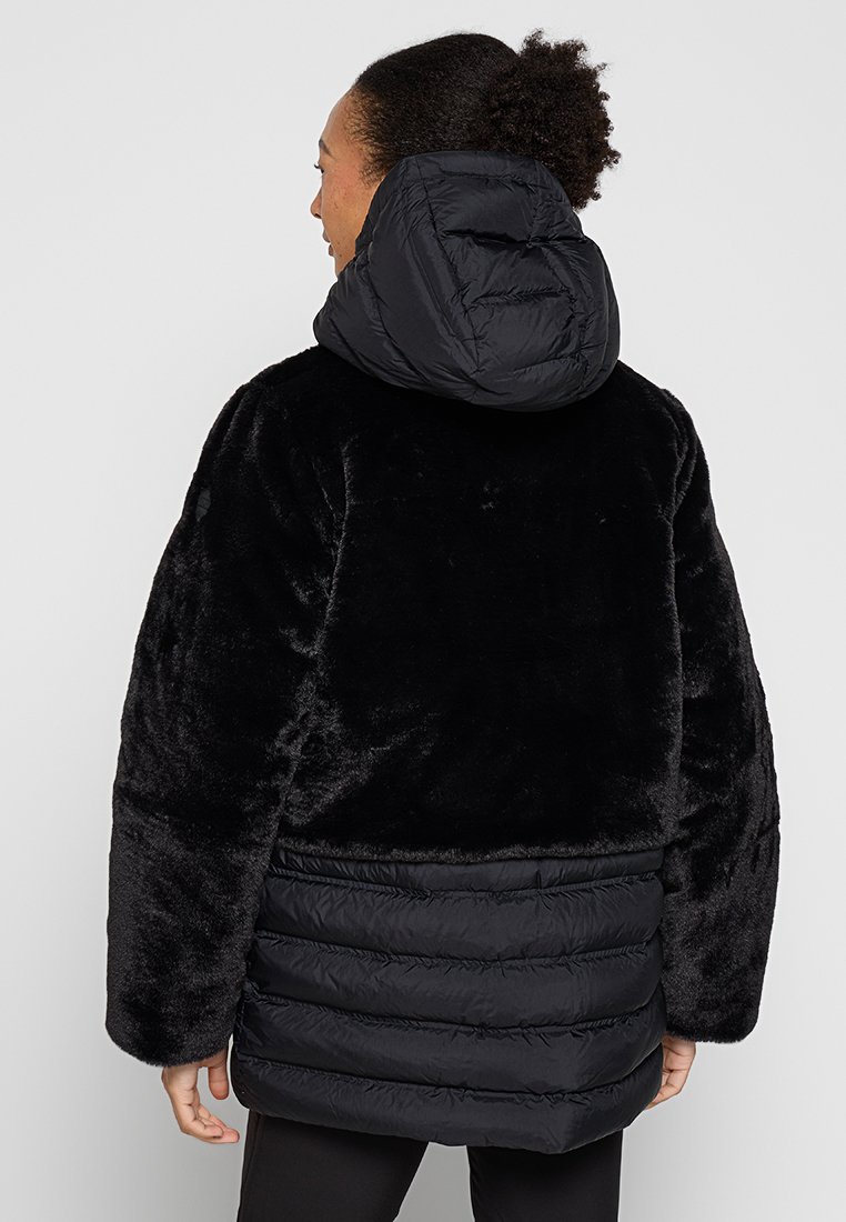 Giacca imbottita in pelliccia sintetica nera, dotata di cappuccio, motivo trapuntato nella parte inferiore e maniche ampie, con una texture morbida.
