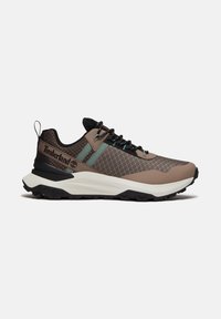 Sneaker da trekking Timberland da uomo marrone e nero con tomaia in tessuto strutturato, dettagli verdi, suola bianca spessa e logo laterale marchiato.