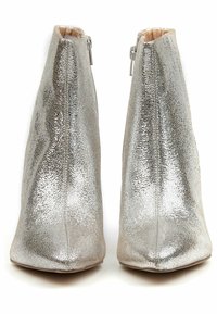 Bottines argentées avec une finition métallisée texturée, bout pointu et fermeture éclair sur le côté. Doublure intérieure lisse et silhouette structurée.