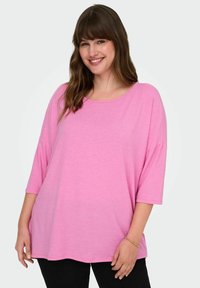 T-shirt rosa oversize con scollatura rotonda e maniche a tre quarti, realizzata in un tessuto leggero, con una vestibilità ampia e una texture liscia.
