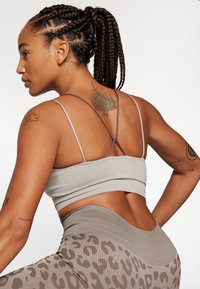 Grijze geribde crop top met dunne bandjes, gecombineerd met high-waisted leggings met een subtiele luipaardprint. Soepele textuur, aansluitend ontwerp.