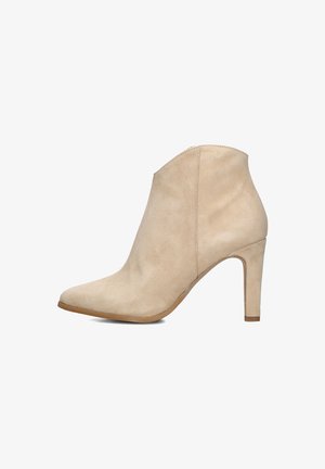 Bottine en daim beige avec un bout pointu et un talon aiguille de 7,5 cm. Présente une texture lisse et peu de détails de couture.