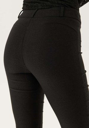 Leggings neri elasticizzati con una texture liscia, design aderente e discreti dettagli delle cuciture sul retro. Vita semplice senza decorazioni.
