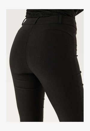 Leggings neri elasticizzati con una texture liscia, design aderente e discreti dettagli delle cuciture sul retro. Vita semplice senza decorazioni.