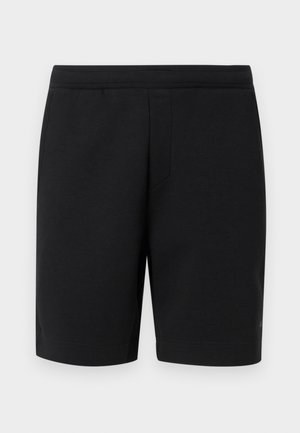 Μαύρα σορτς μέχρι το γόνατο με επίπεδη μέση και διακριτική λεπτομέρεια ραφής μπροστά, εμφανίζονται σε απλό φωτεινό φόντο.