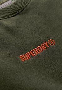 Donkergroen sweatshirt met een oranje geborduurd "SUPERDRY" logo. Ribbelkraag en zachte stofstructuur.