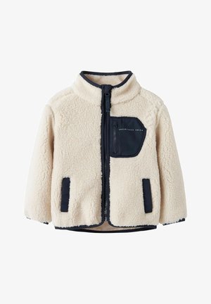 Flis jakna u svijetlo krem boji s tamnoplavim detaljima, s patentnim zatvaračem sprijeda, visokim ovratnikom i jednim prsnim džepom u dijagonalnom dizajnu.