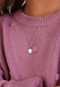 Zilveren halsketting met een paard-vormige hanger, rustend tegen een zachte, gestructureerde, roze gebreide trui met een geribde kraag.