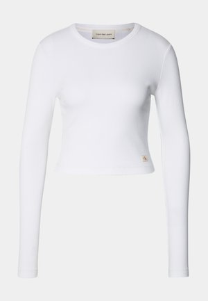 Top cropped de manga longa branco, feito de tecido canelado. Apresenta um decote redondo e uma pequena etiqueta de logotipo no canto inferior esquerdo.