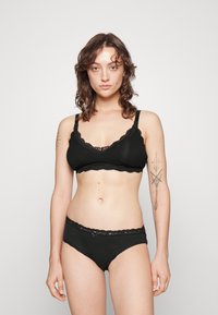 Black cotton bra with lace trim and adjustable straps, paired with matching black lace-accented panties. Flat waistband and a simple design.