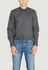 Camicia a maniche lunghe con motivo in bianco e nero, dotata di colletto a bottoni, abbinata a jeans in denim azzurro chiaro, con cinque tasche e passanti per cintura.