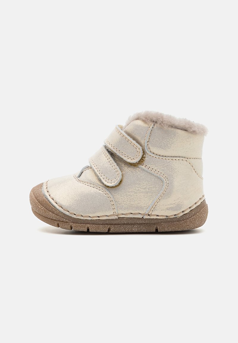 Bottes en daim de couleur crème avec une doublure en fourrure douce, dotées de deux brides Velcro ajustables et d'une semelle en caoutchouc texturée.