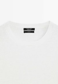 Witte linnen trui met een ronde hals en subtiele textuur. Zichtbare labels met het merk "Massimo Dutti" en de samenstelling van de stof.