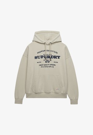 Sudadera con capucha beige con bolsillo delantero y texto "Superdry" en azul marino junto con un logo de estilo vintage impreso en el pecho.