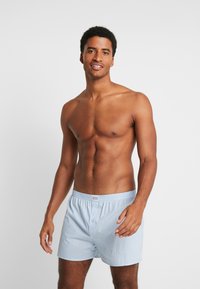 Ljusblå randiga kalsonger med elastisk midja och knäppning fram. Tillverkade av mjukt material, med en avkopplad passform och inga ytterligare mönster.