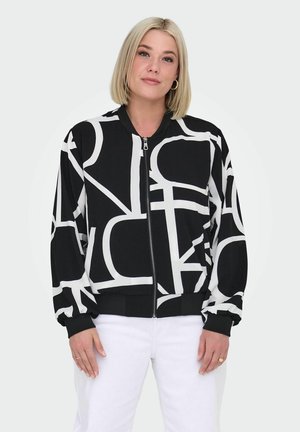 Black bomber jacket featuring large white abstract patterns, zip closure, and ribbed cuffs. Worn over white pants, smooth fabric texture.
