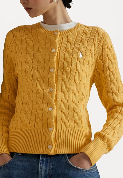 Gelbes, kabelgestricktes Cardigan mit rundem Ausschnitt, Knopfverschluss, gerippten Bündchen und Saum. Kleines Logoschildchen auf der linken Brust.