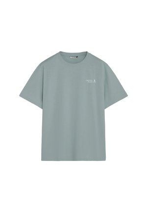 Camiseta azul claro de cuello redondo con mangas cortas y texto "Creative Studio" con un pequeño icono de calavera en la parte superior izquierda del pecho.