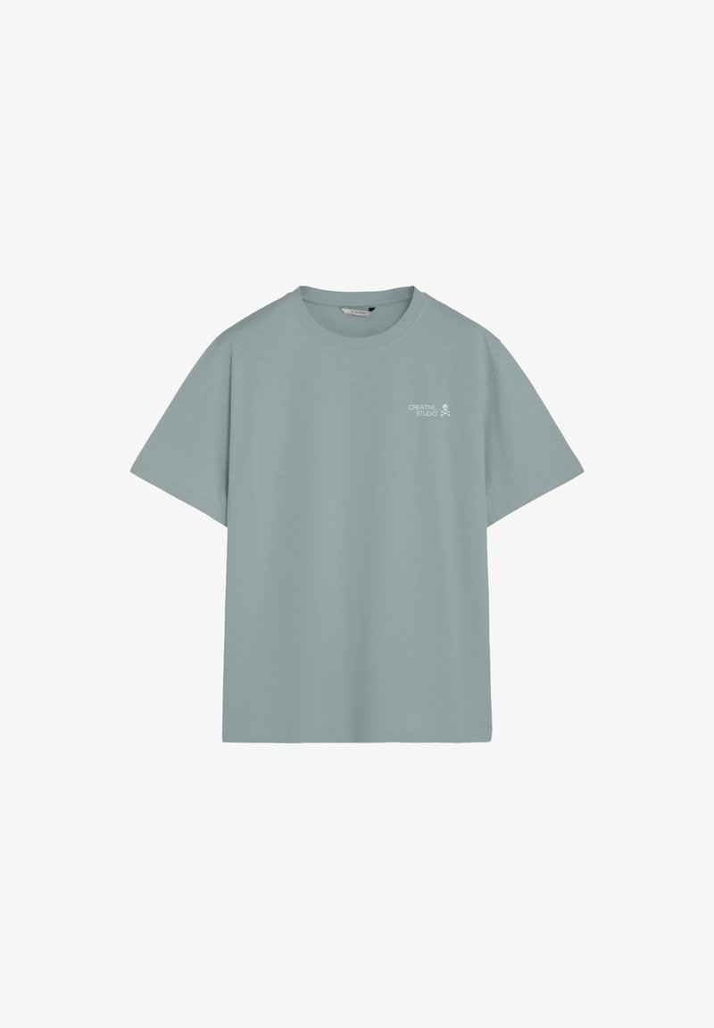 T-shirt bleu clair à col rond avec manches courtes et texte « Creative Studio » accompagné d'une petite icône de crâne sur la partie supérieure gauche de la poitrine.