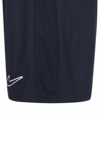 Marineblaue Sportshorts aus leichtem Stoff mit glatter Textur. Mit einem weißen gestickten Logo auf der linken Seite.