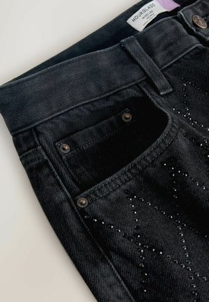 Black denim wide-leg jeans with a front pocket, metal rivets, and black rhinestone star embellishments on the thigh.