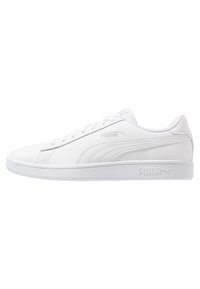 Sneaker bianco con superiore in sintetico liscio, punta arrotondata e chiusura con lacci. Presenta il logo Puma in argento e suola in gomma testurizzata.
