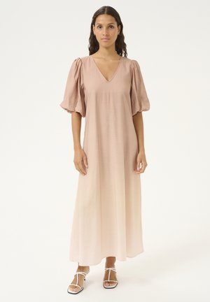 Langes, hellrosafarbenes Kleid mit V-Ausschnitt, Puffärmeln und fließender Silhouette. Der Stoff hat eine glatte Textur, die durch einfache weiße Sandalen ergänzt wird.