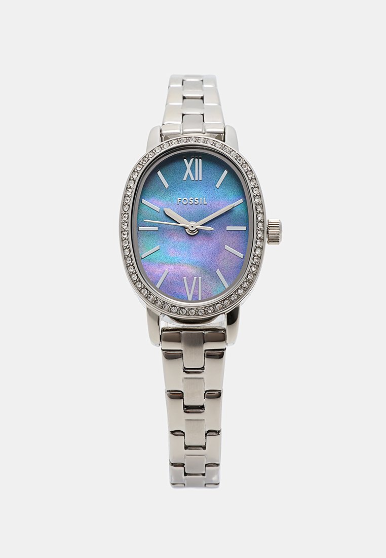 Montre-bracelet en métal argenté avec un cadran ovale, un cadran bleu irisé, des chiffres romains et une lunette scintillante. Bracelet de style maillon.