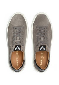 Zapatillas de ante gris con punta redonda, cordones texturizados y suela de goma blanca. Presenta un logo en blanco y negro en la lengüeta y una plantilla beige.