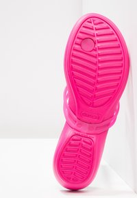Ljust rosa Crocs sandal sula med texturerad greppmönster, ventilationshål nära tån och varumärkeslogotyp på vit bakgrund.