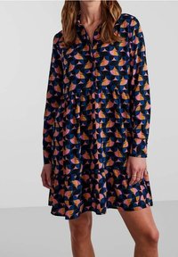 Abito camicia a maniche lunghe in tessuto blu navy, caratterizzato da un motivo geometrico di forme rosa, arancioni e crema, con colletto a bottone e gonna a balze.