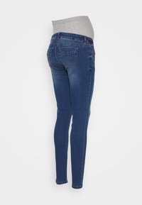 Dark blue maternity jeans with stretchy gray waistband, shown on a standing person from the back against a plain white background.