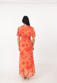 Maxiklänning i genomskinlig orange tyg med blommönster, korta ärmar, smockad midja och rak skärning som når till mitten av vaden med en flödig design.