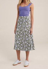 Pitkä vihreä hame, jossa on valkoisia ja laventelinvärisiä kukkia, yhdistettynä purppuraan istuvaan paitaan ja valkoisiin lenkkareihin. Helma on liehukkatyyppinen ja siinä on sivureikä.