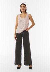 Helles rosa, Pailletten besetztes Tanktop kombiniert mit hoch taillierten, weitbeinigen, dunkelgrauen Jeans und schwarzen, hochhackigen Schuhen. Glatte Textur und lässiges Design.