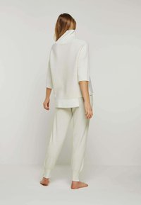 Hellbeige, oversized Pullover mit Kragen und kurzen Ärmeln, kombiniert mit passenden, weichen, locker sitzenden Hosen mit gerippten Bündchen.