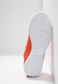 Zapatilla de running Adidas con parte superior de color rojo brillante y suela de goma blanca texturizada. Cuenta con una suela con patrón para mejor tracción y el logo en el lateral.