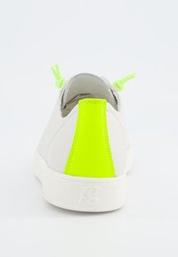 Weißer Sneaker mit einer neongrünen Fersenschlaufe und passenden Schnürsenkeln. Verfügt über eine strukturierte Sohle und ein glattes Lederobermaterial.