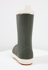 Zelená gumová čižma s bielou podrážkou, s textúrovaným povrchom a pruhovaným akcentom pri vrchu. Navrhnutá na nepremokavé nosenie.